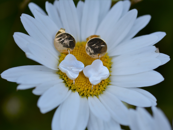 paire de boucles d'oreille dorée accrochée sur une fleur.