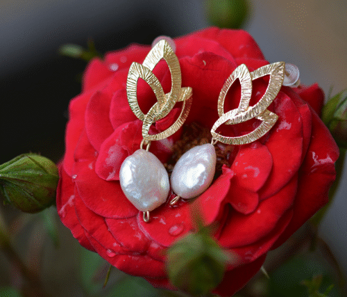 paire de boucles d'oreille dorée accrochée sur une fleur.