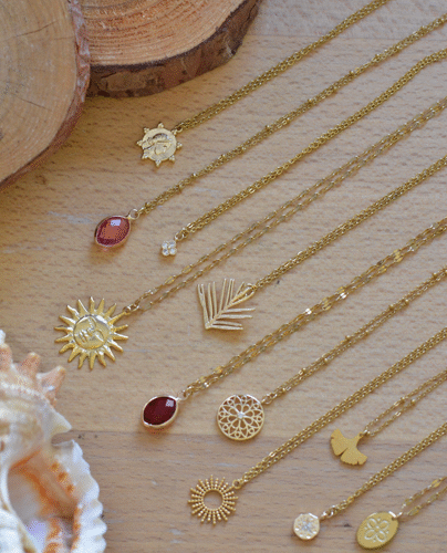 onze chaînes dorés avec des pendentifs dorés posés sur une table