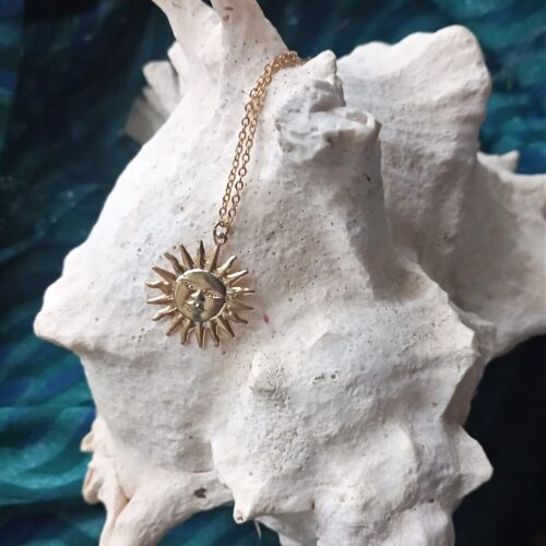 une chaine et un pendentif doré sur un coquillage