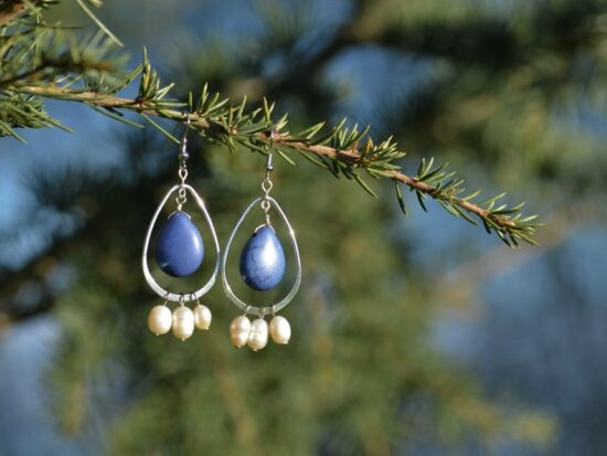 paire de boucles d'oreille avec une boucle, une pierre bleue et des perles sur une branche.