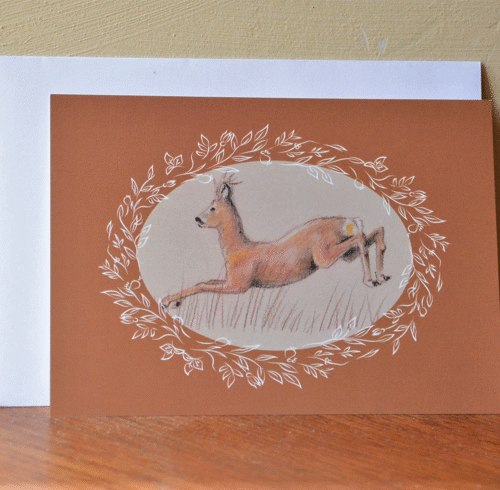 carte postale de chevreuil et enveloppe posés contre un mur.