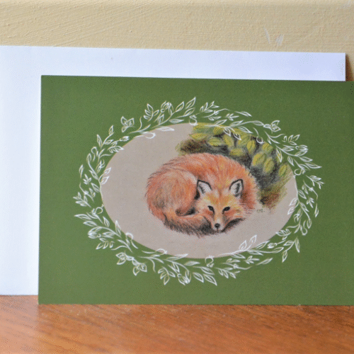 carte postale de renard et enveloppe posés contre un mur.