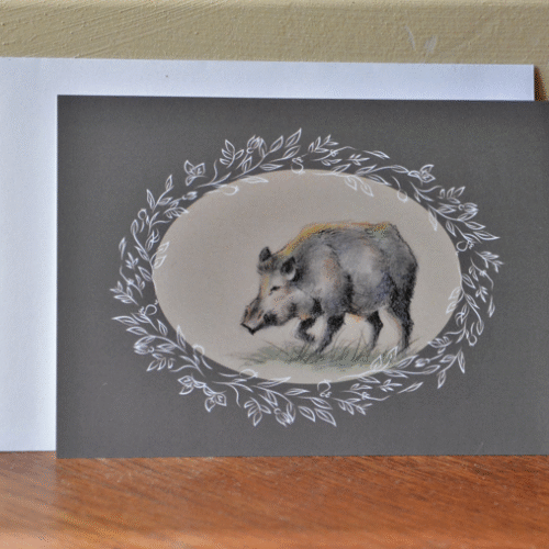 carte postale de sanglier et enveloppe posés contre un mur.