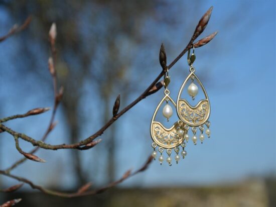 paire de boucles d'oreille, avec un chandelier de perles, accrochée sur une branche.