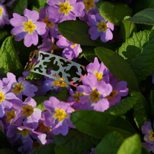 bracelet doré ajouré posé dans les fleurs.