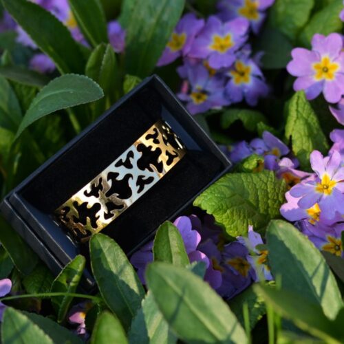 bracelet doré ajouré posé dans les fleurs.