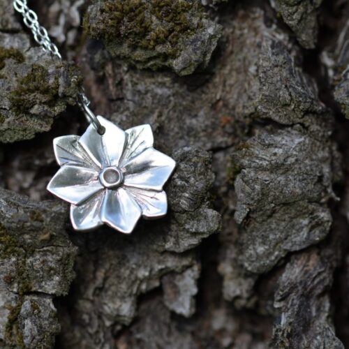 pendentif en argent représentant une fleur avec 4 pétales et 4 feuilles.