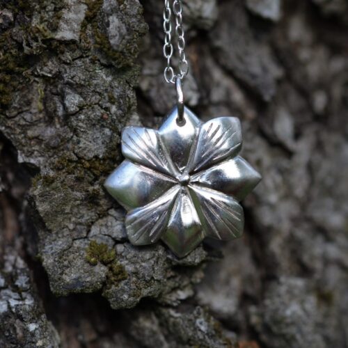 pendentif en argent représentant une fleur avec 4 pétales et 4 feuilles.