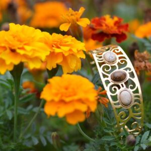 Manchette écorce dorée ajourée posée dans les fleurs, avec des pierres de jaspe