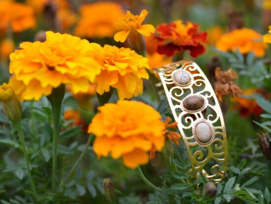 Manchette écorce dorée ajourée posée dans les fleurs, avec des pierres de jaspe