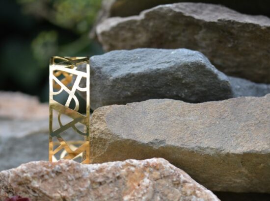 bracelet doré ajouré style art déco posé sur une pierre, Manchette Arcs et lignes
