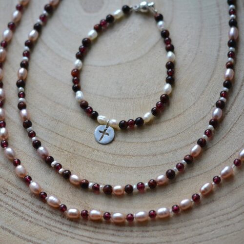 bracelet crux et colliers bijoux disposés sur une planche de bois