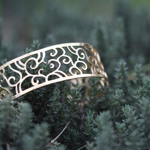 bracelet doré ajouré posé dans une plante.