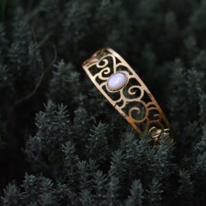 bracelet Coeur de nacre doré ajouré posé dans une plante, avec une nacre.