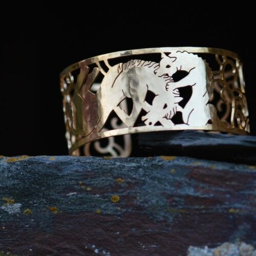 manchette attaque du lion en laiton plaqué or ajouré posé sur une pierre