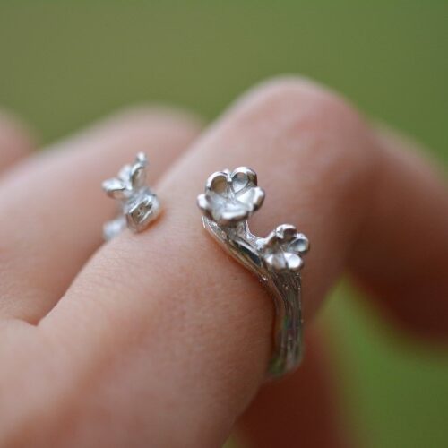 bague trois fleurs en argent portée sur une main