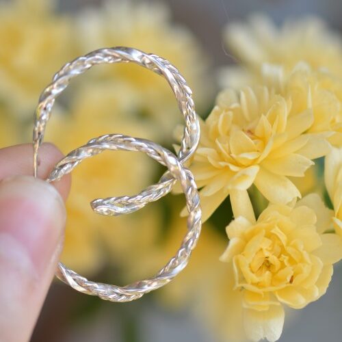 une paire de créole en argent devant des fleurs