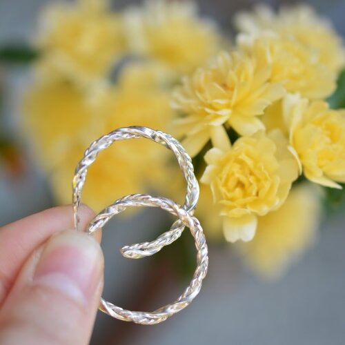 une paire de créole en argent devant des fleurs