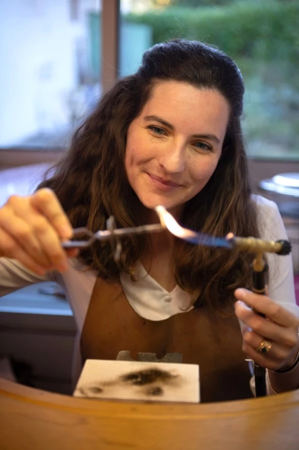 la créatrice Constance travaille au chalumeau un bijou dans son atelier d'art